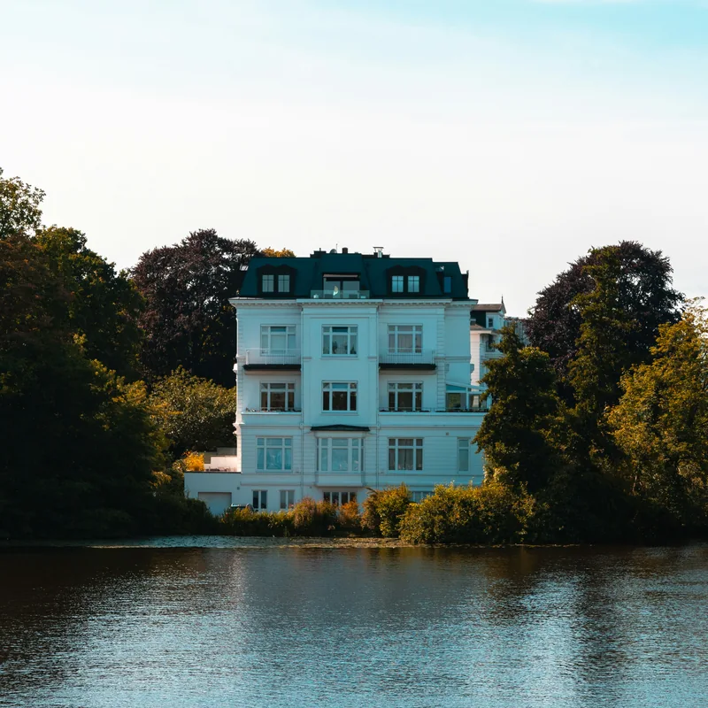 Helles Haus mit Bäumen am Wasser